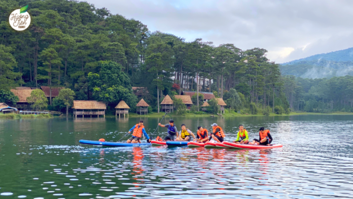 Group stand-up paddleboarding on Tuyen Lam Lake in Dalat, surrounded by serene landscapes.