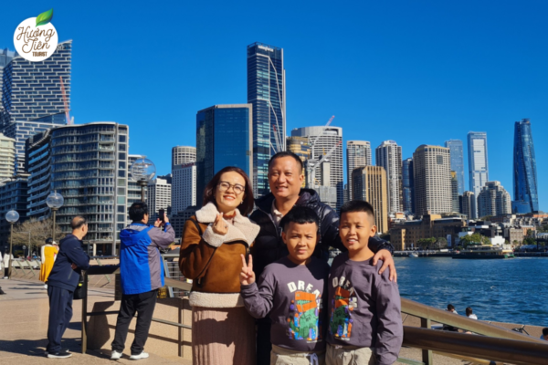 Gia đình du lịch Sydney tại Circular Quay với tòa nhà chọc trời phía sau.